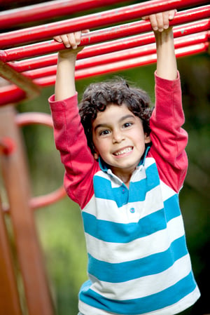 Boy playing at the monkey bars and smiling