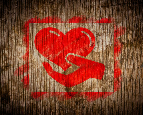 Charity. Red Icon of Heart in the Hand Painted by Stencil on Wood. Grunge Background.
