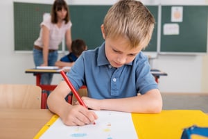 Cute Male Kindergarten Answering a Test at his Table Inside the Classroom Seriously.