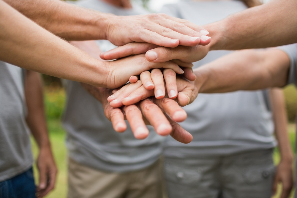 Group of hands stacked in the middle of a circle of people