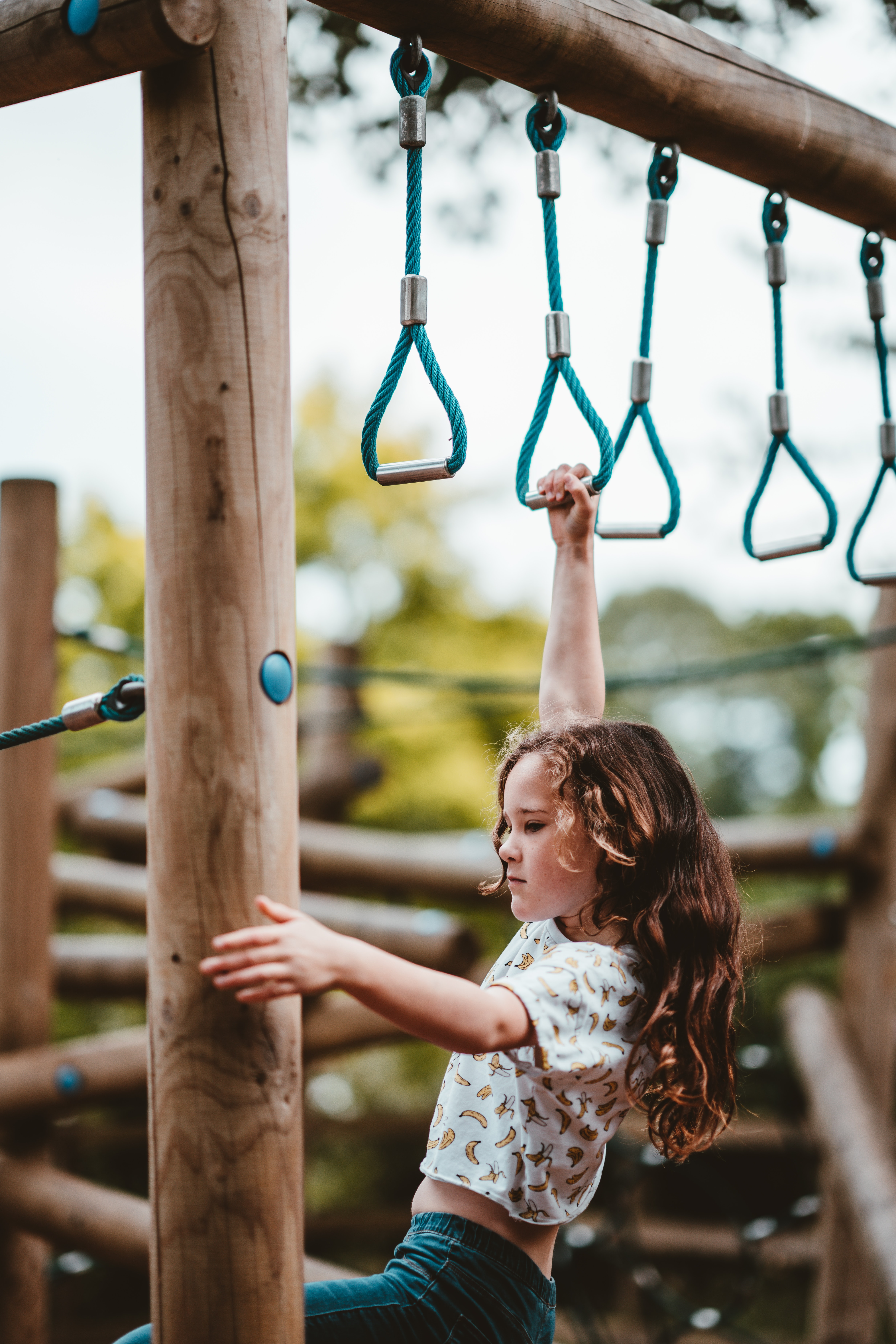 May Recreation Climbing for Success? Yes We Can! Girl Holding on to Hanging Rings with One Hand Climbing on to Ladder