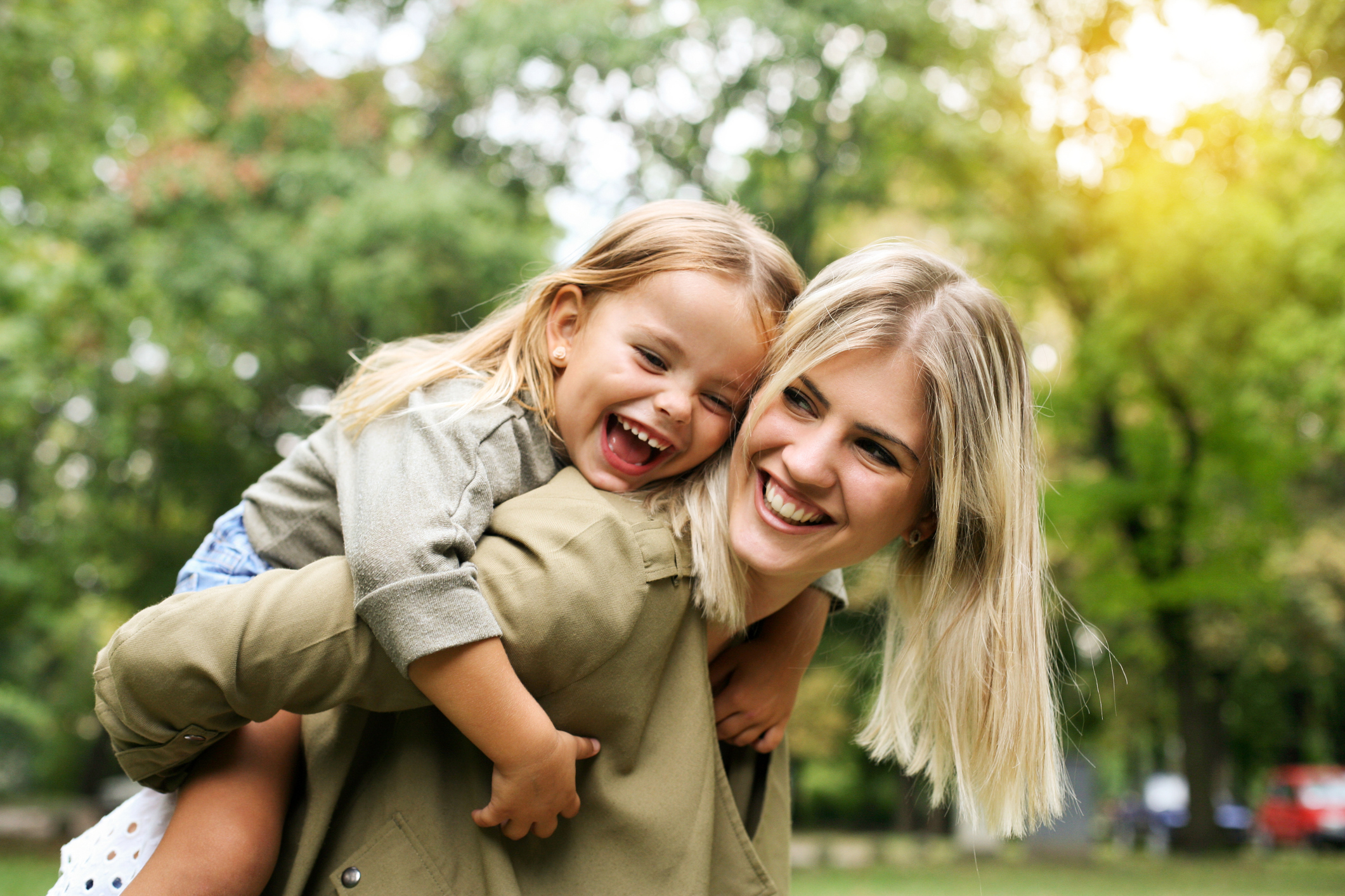 Little girl on a piggy back ride with her mother at park