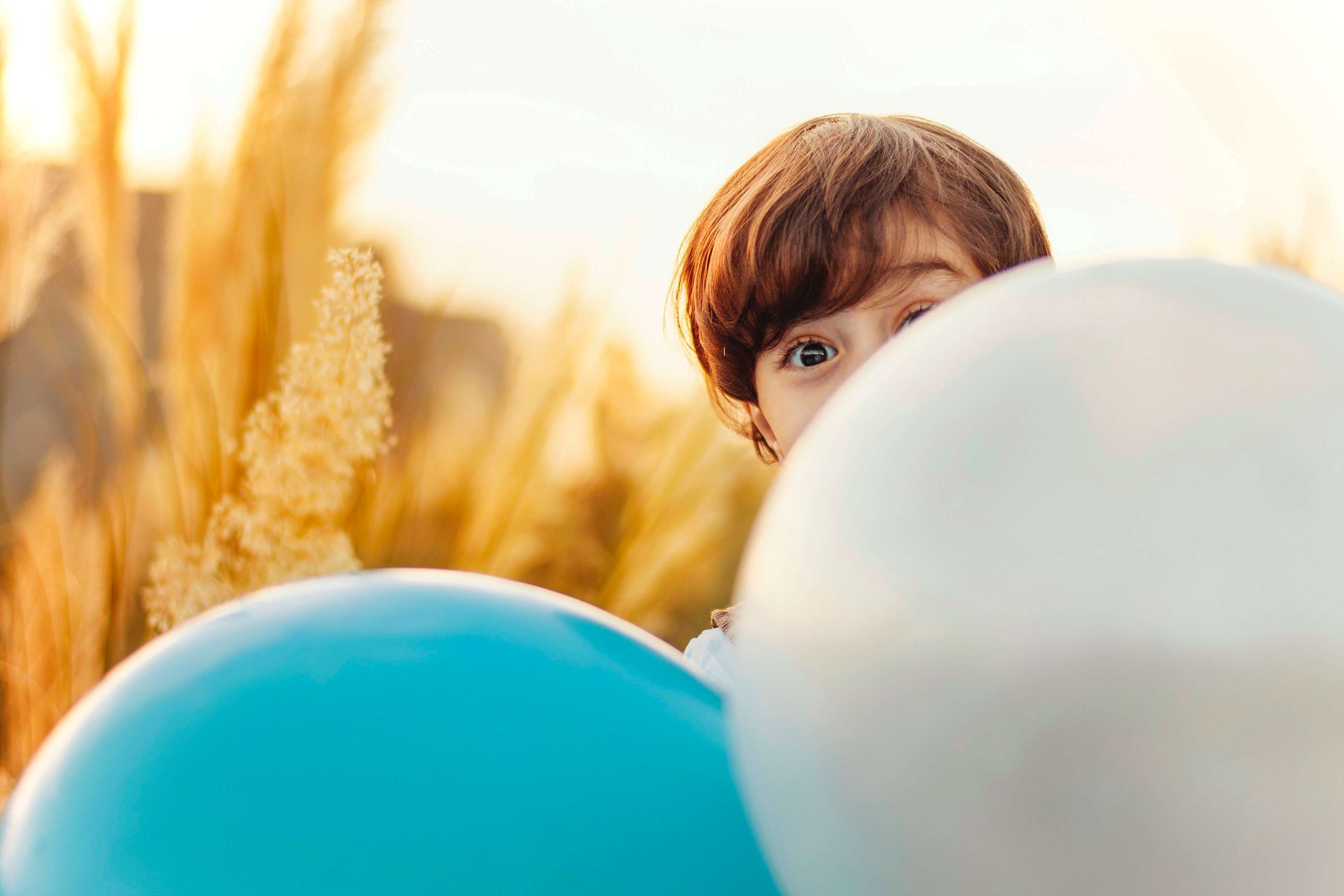 May Recreation Mental Health Month Kids Edition Boy in Wheat Field Hiding Behind Large Baloons